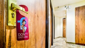 Entrada de un hotel con una puerta de madera, un cartel de 'NO MOLESTAR' y un suelo de mármol.
