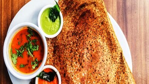 Una dosa triangular con tres salsas sobre un plato blanco.