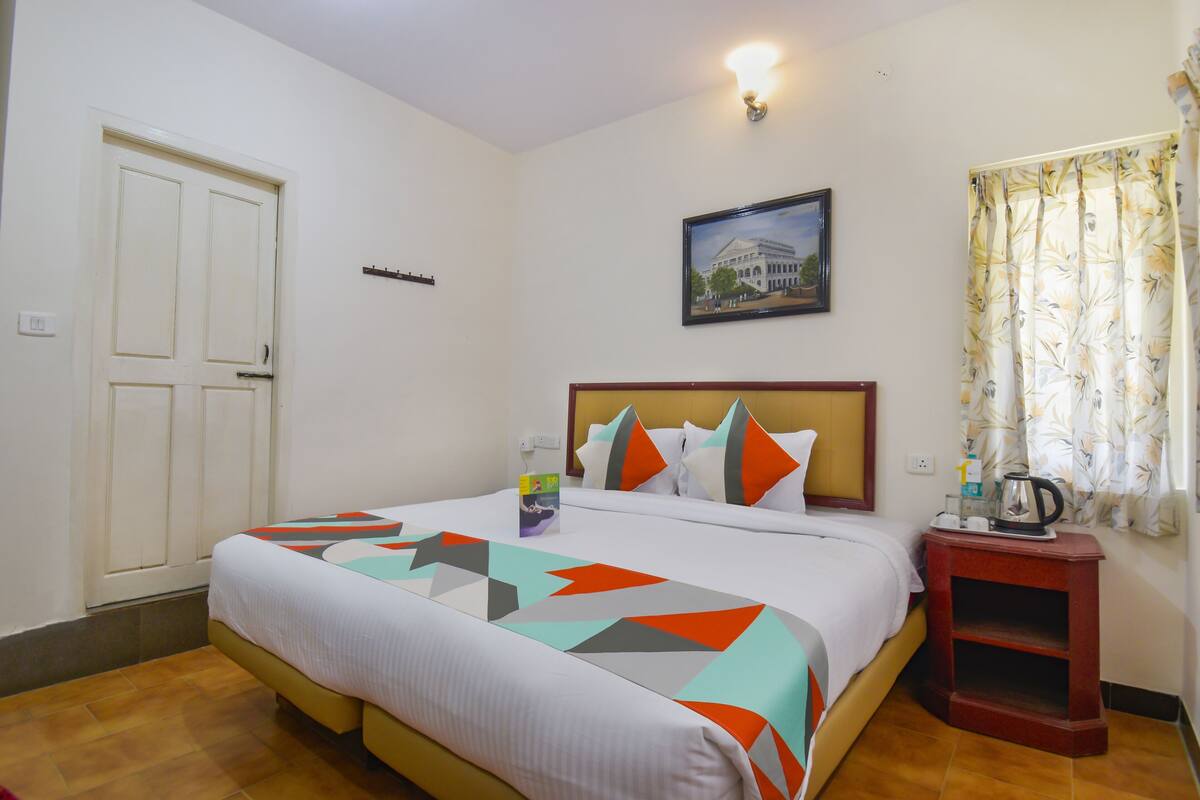 A hotel room with a bed, a nightstand, a painting, and a door.