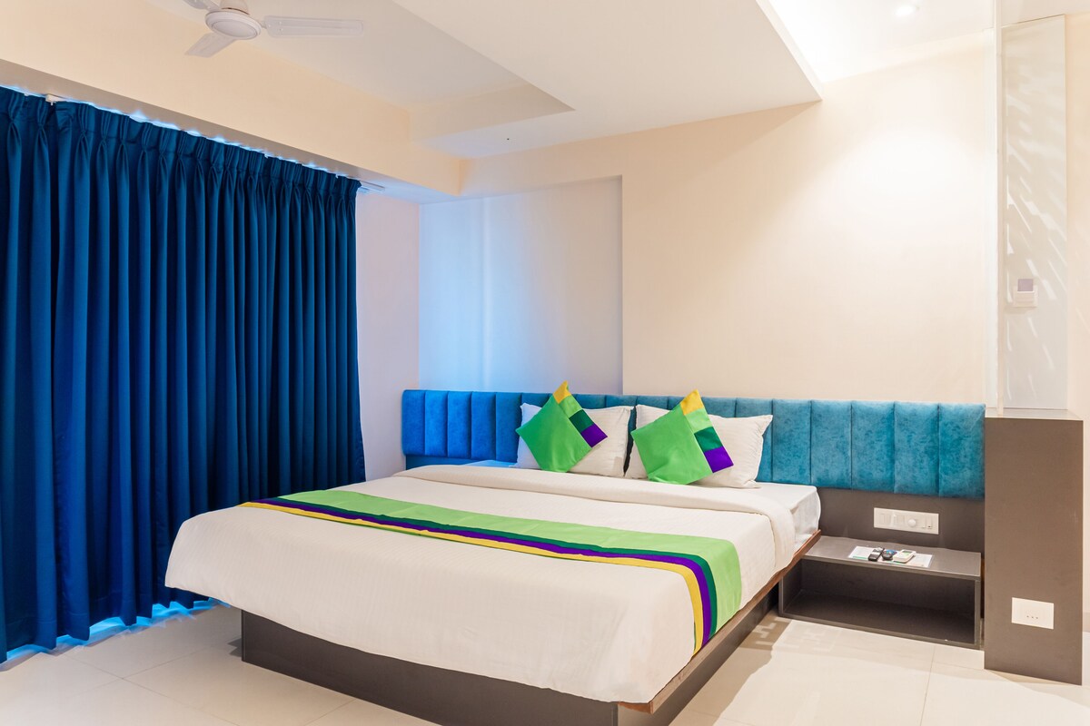 A modern hotel room with a large bed, a nightstand, and a ceiling fan.