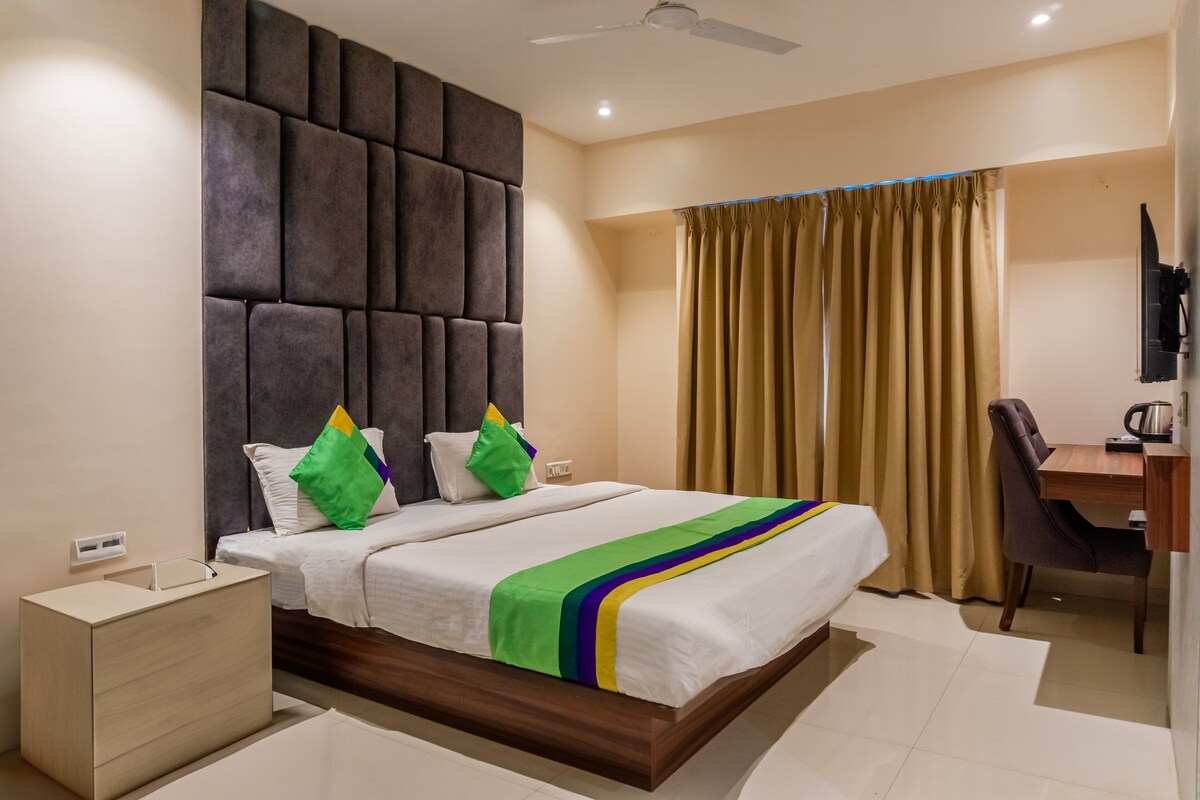 A modern hotel room with a large bed, a desk, and a chair.