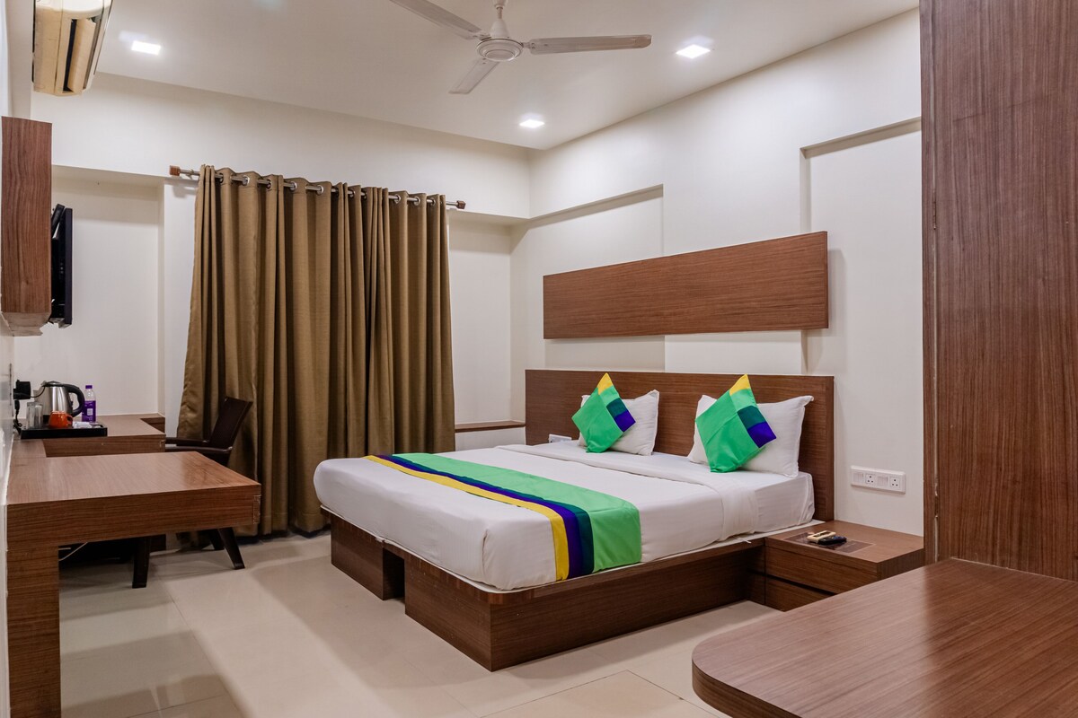 A hotel room with a wooden bed, a desk, a chair, a TV, and a ceiling fan.