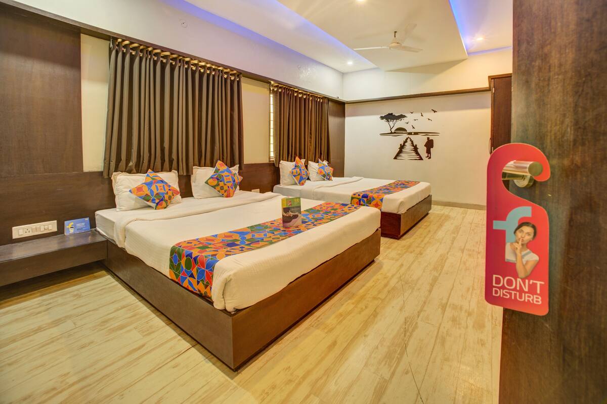 A hotel room with two beds, a wooden floor, a ceiling fan, and a 'Don't Disturb' sign.