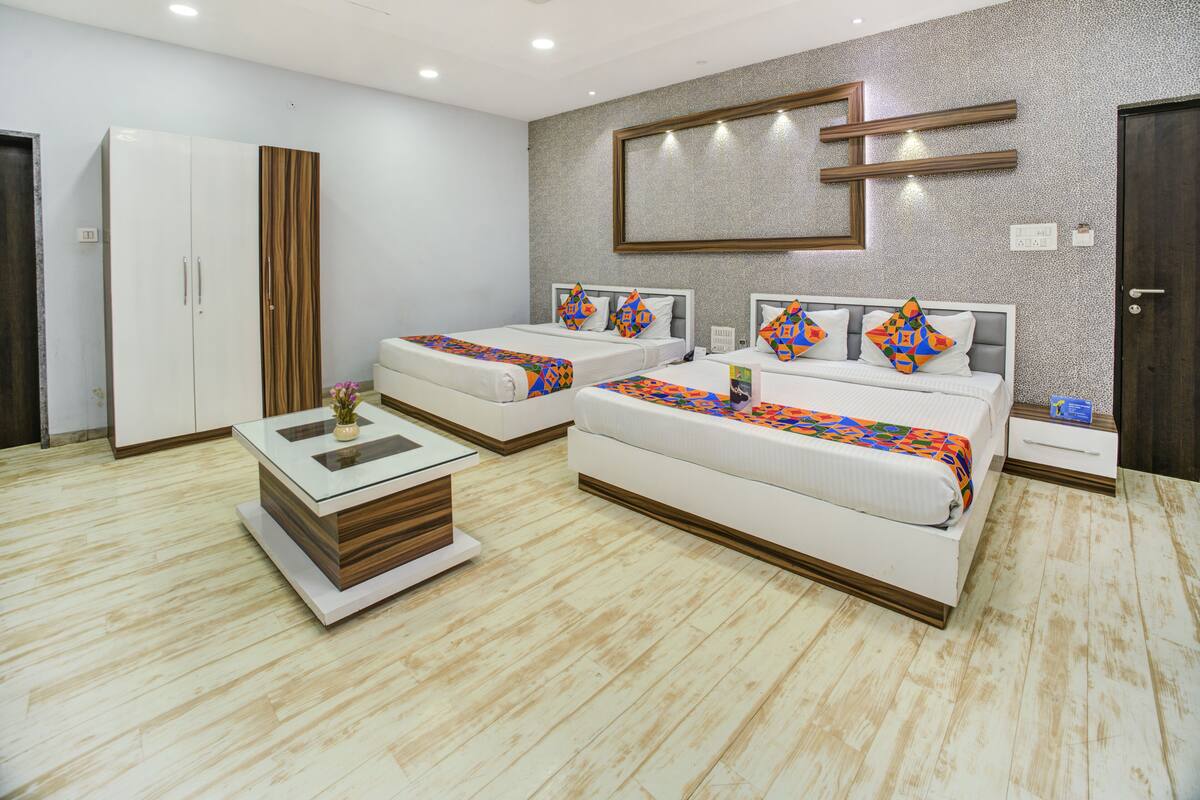 A hotel room with two beds, a wardrobe, a small table, and a decorative mirror.