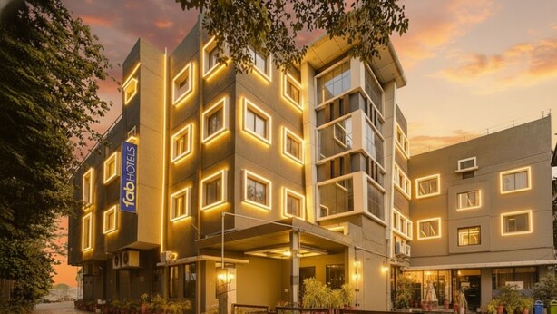 A modern hotel with a geometric facade, multiple balconies, and a well-lit entrance. - FabHotel Bee Town - AB Road (Indore)