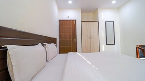 A hotel room with a large bed, wooden wardrobe, and a mirror on the wall. - Fabhotel Casa (Mohali)