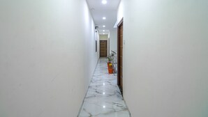 A narrow hallway with white walls and a marble floor. - Fabhotel Casa (Mohali)