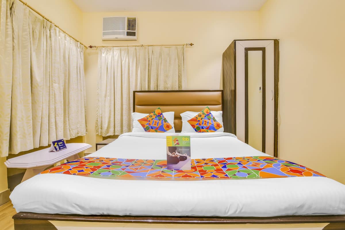 A hotel room with a bed, a nightstand, a wardrobe, and a curtain.