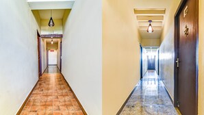 Um corredor com piso de azulejos, iluminação no teto e porta com puxador de latão.