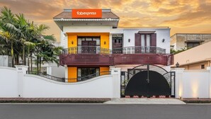 Um edifício com a placa 'fabexpress', entrada com portão e varanda com corrimão.