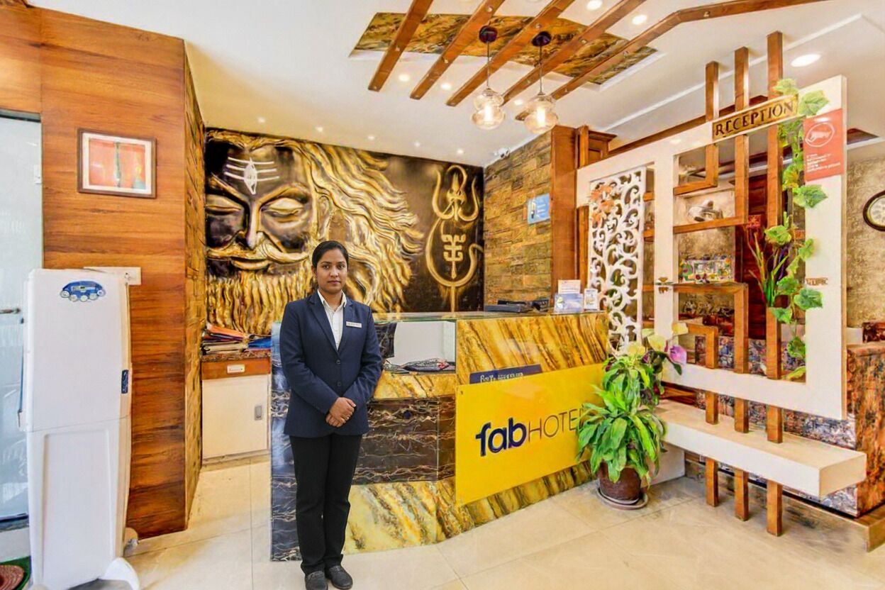 A hotel reception area with a marble counter, a receptionist, and a reception desk.