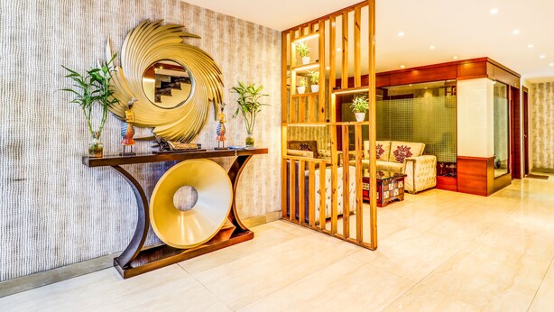 Un interior moderno con un espejo grande, una consola decorada con objetos decorativos y una zona de estar con un sofá acolchado y una mesita.