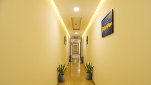 A hallway with a yellow wall, potted plants, and a framed picture. - Fabexpress Comfort Executive (Paud)