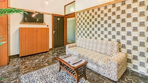 Un vestíbulo de hotel con una pared a cuadros, un sofá, un aparador de madera y un piso de baldosas.