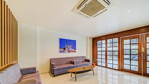 Sala de estar moderna com sofá, mesa de centro e uma grande janela com vista para um edifício.