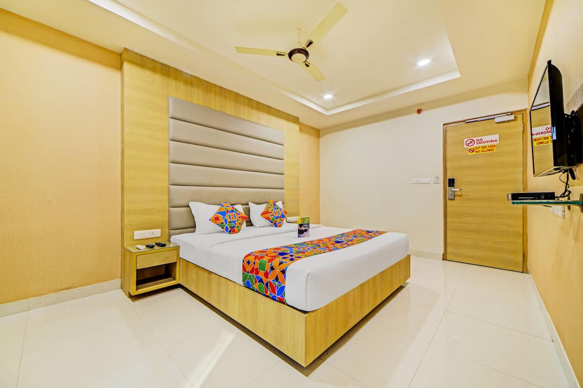 Een moderne hotelkamer met een houten bed, een plafondventilator, een televisie en een rookvrij bordje op de deur.