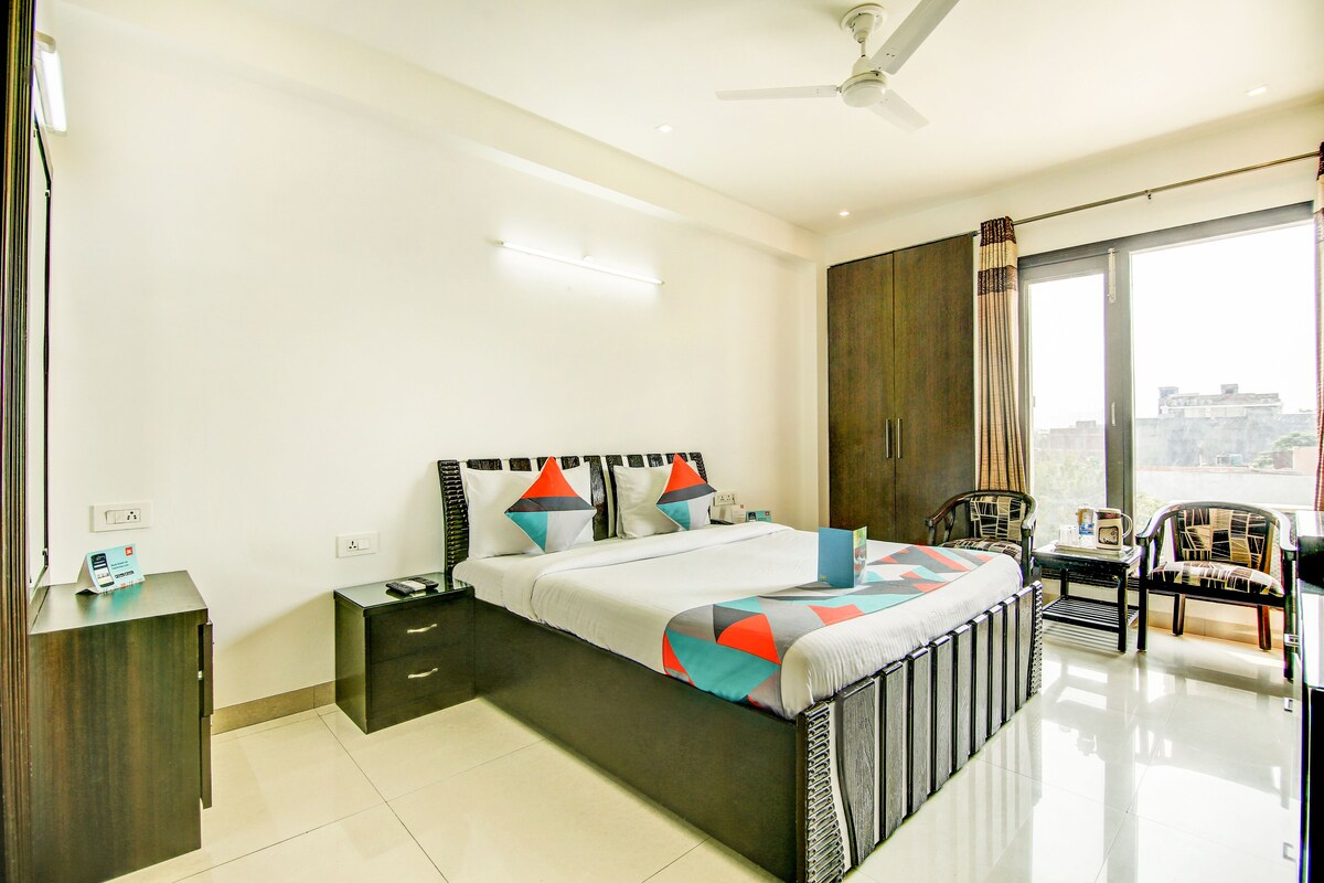 A modern hotel room with a large bed, a desk, and a chair.
