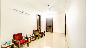 A hallway with two wooden chairs and a small table, a ceiling fan, and a door leading to another room. - Via Hemkunt Residency - Nr Yatharth Super Speciality Hospital - Noida 110 (Noida)