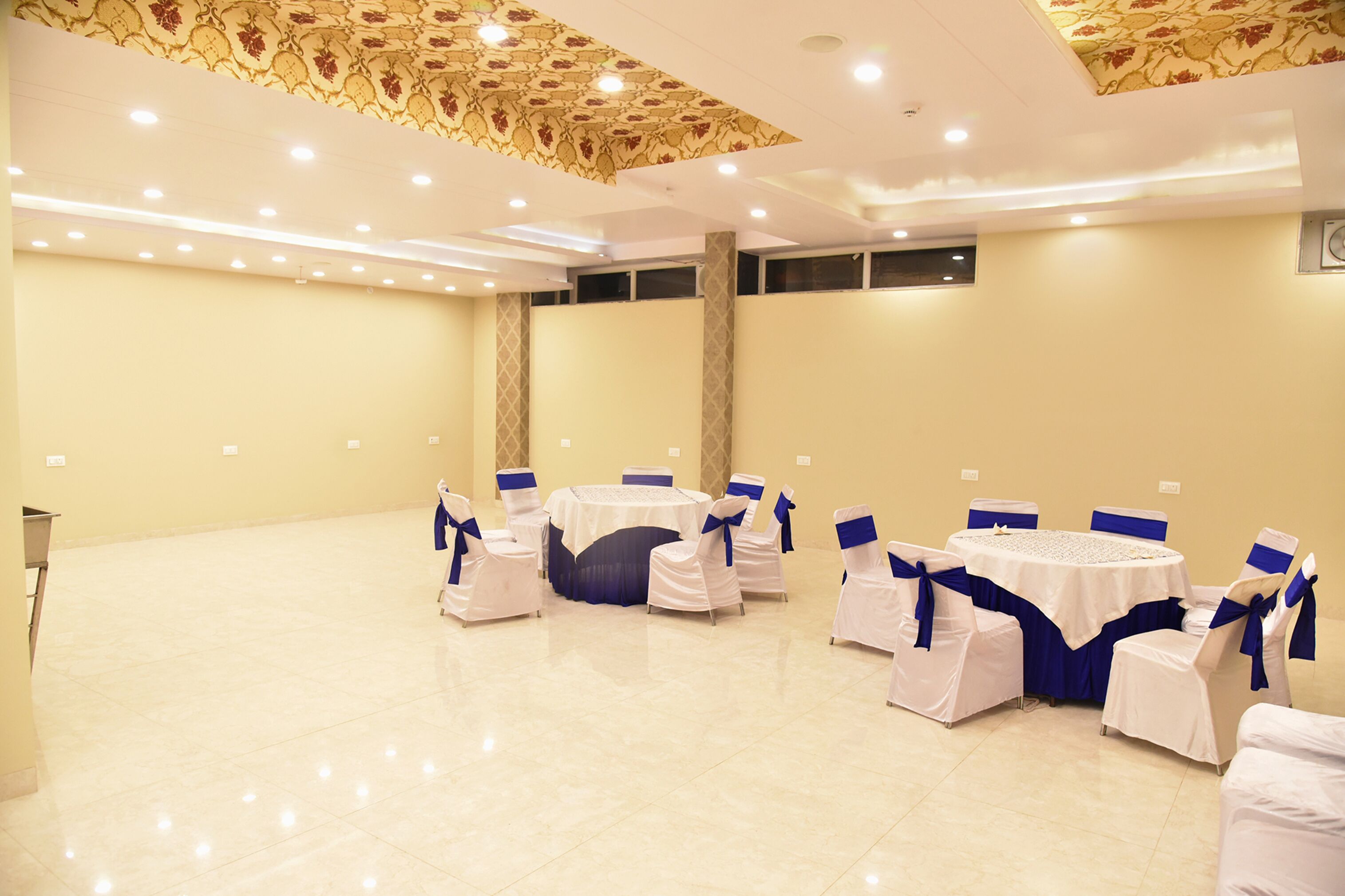A conference room with round tables and chairs, beige walls, and a patterned ceiling.