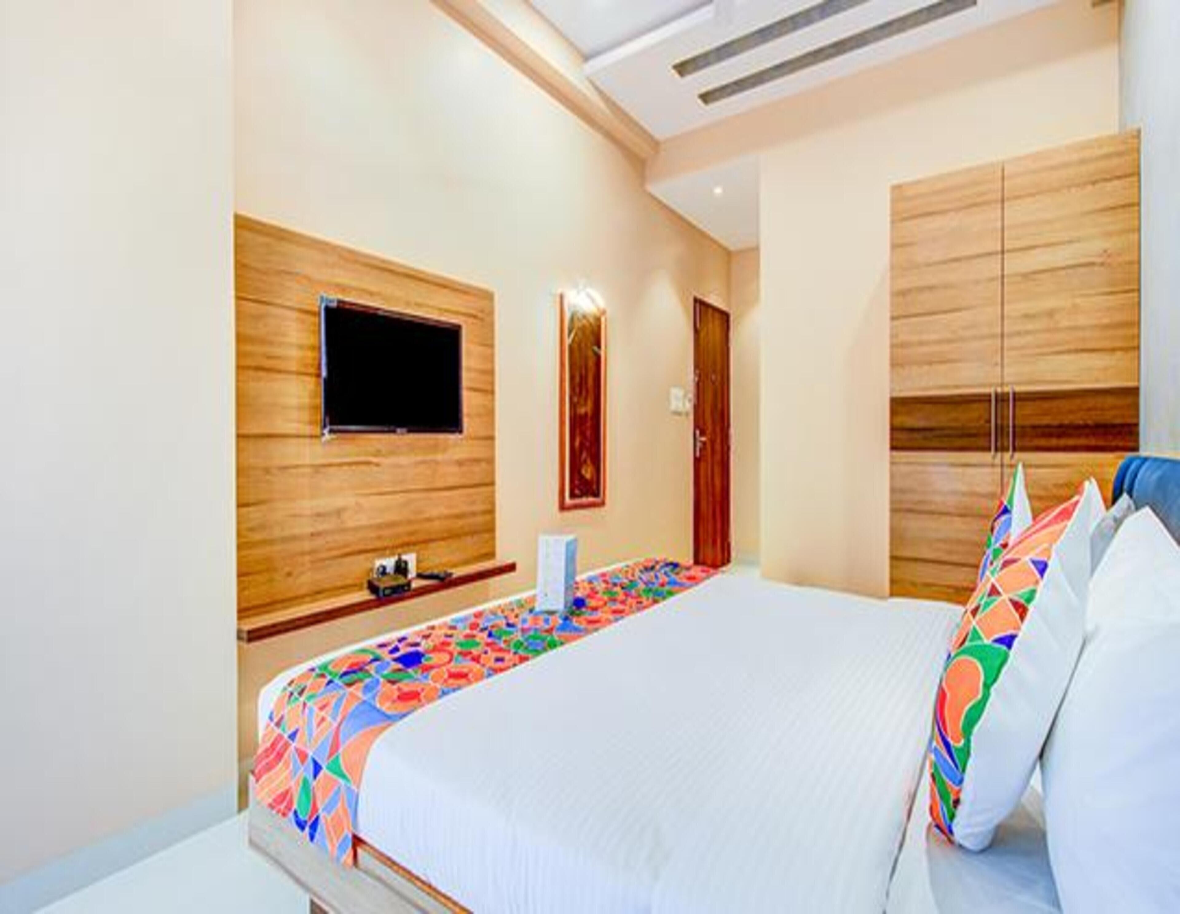 A modern hotel room with a large bed, a flat-screen TV mounted on the wall, and wooden paneling on the walls.