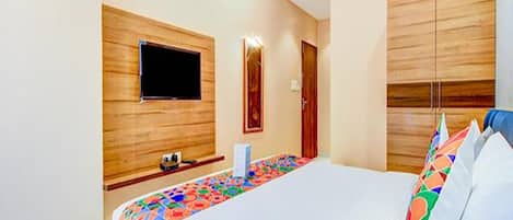A modern hotel room with a large bed, a flat-screen TV mounted on the wall, and wooden paneling on the walls.
