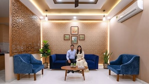 A reception area with a blue sofa set, a coffee table, and decorative plants. - Fabhotel 7Th Crossing (Jaipur)