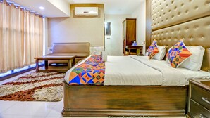 A hotel room with a large bed, a sofa, a desk, and a wardrobe. - Fabhotel Anandam (Raipur)
