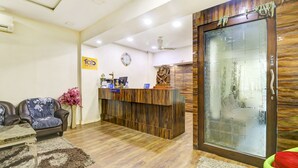 A reception area with a wooden reception desk, a clock, and a 'PUSH' sign on a door. - Fabhotel Anandam (Raipur)