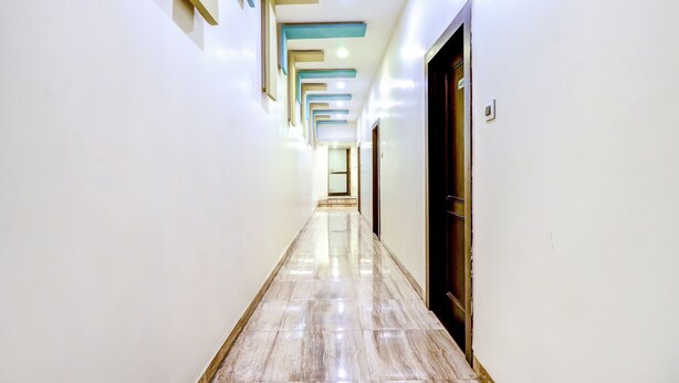 A long, narrow hallway with a polished marble floor and a series of recessed ceiling lights. - Fabhotel Anandam (Raipur)