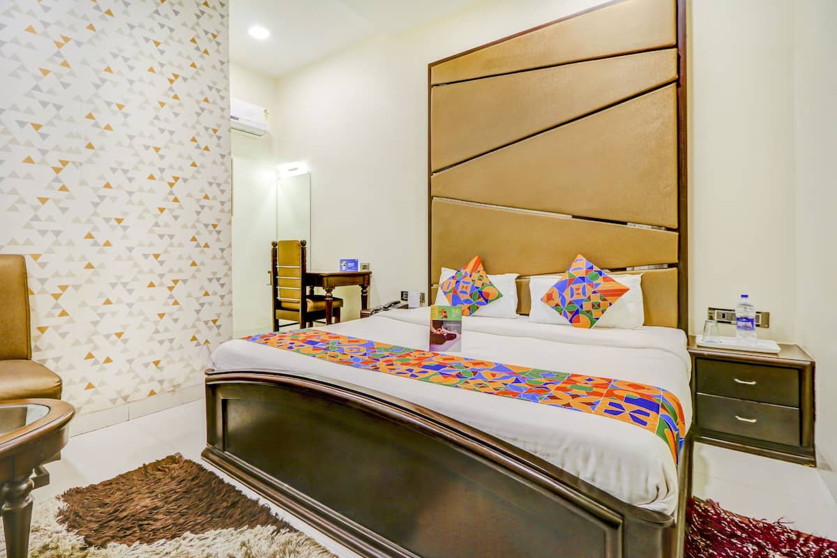 Une chambre d’hôtel bien rangée, avec un grand lit, une table de chevet, une chaise et un miroir au mur.