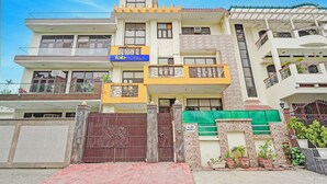 A multi-story building with a yellow and white facade, a gated entrance, and balconies with decorative railings. - FabHotel The Everest 43 (Noida)