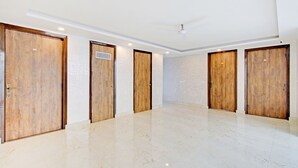 A hotel room with a marble floor, wooden doors, and a ceiling fan. - Fabhotel Soft Petals (Gurugram)