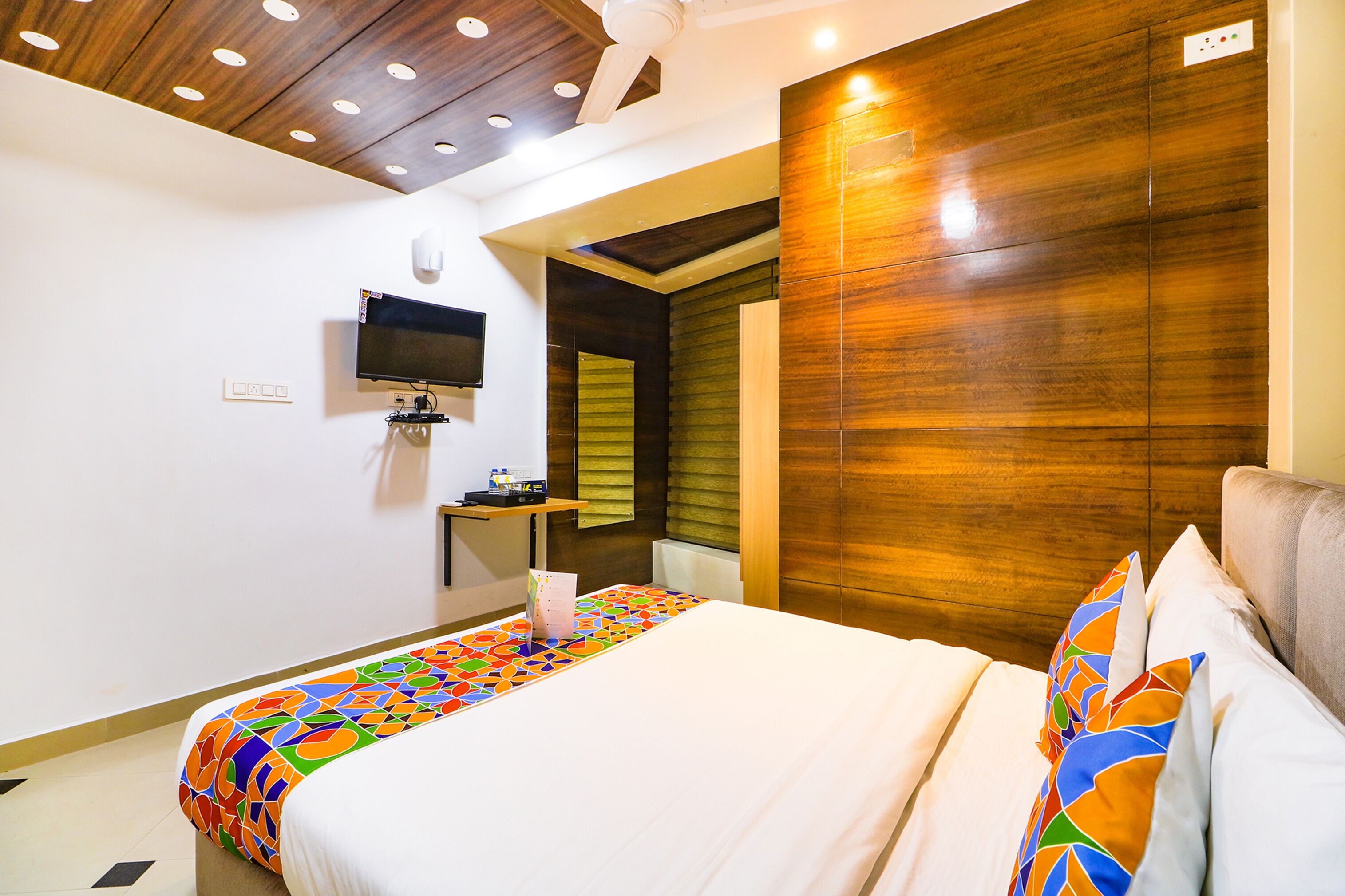 Une chambre d’hôtel avec un lit, une télévision, une petite table et un mur décoratif en bois.