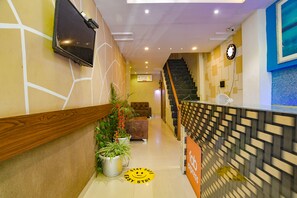 Un hall d’accueil d’hôtel avec un escalier, une horloge et un panneau indiquant « Séjour facile ».