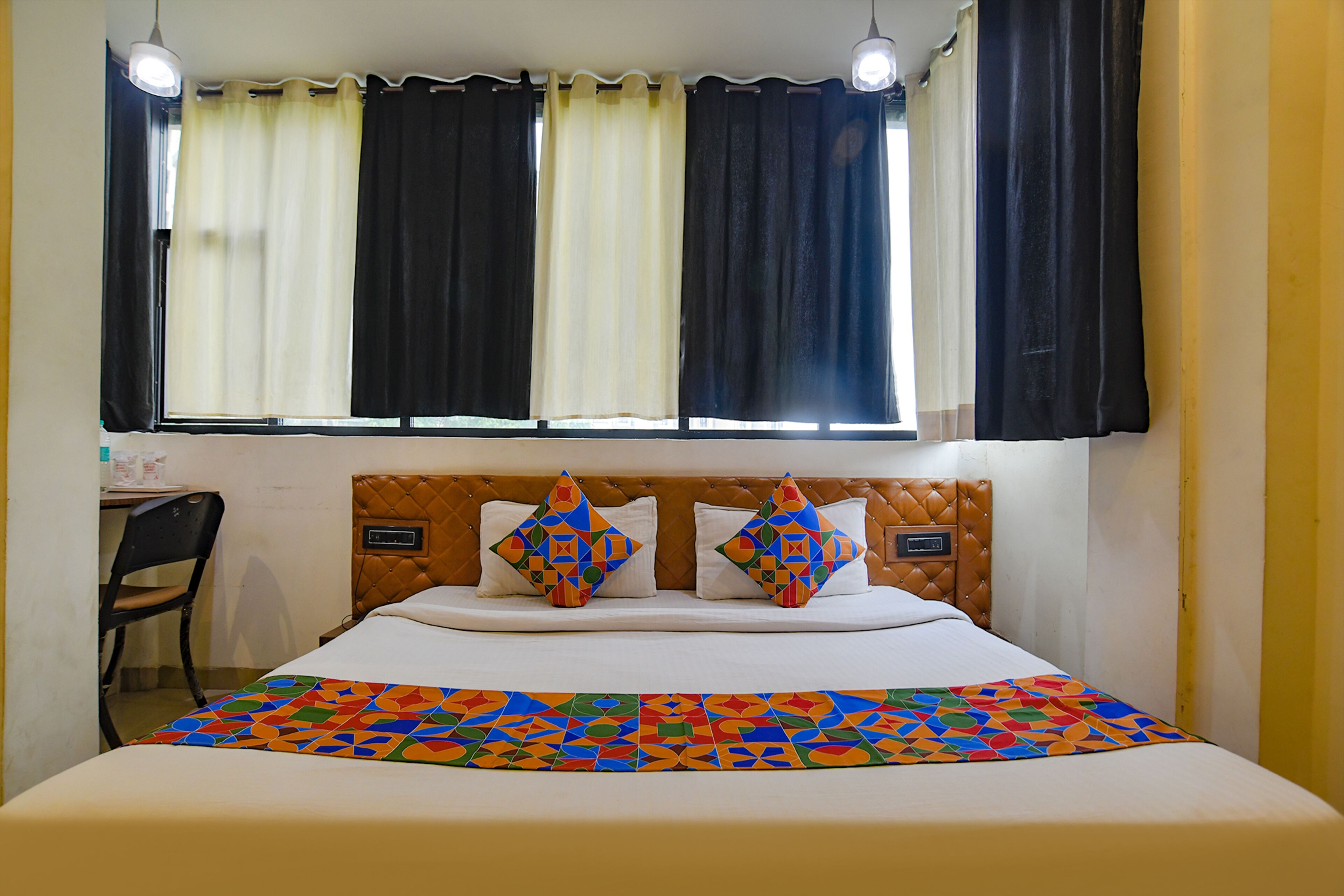 A hotel room with a bed, a desk, and a chair.