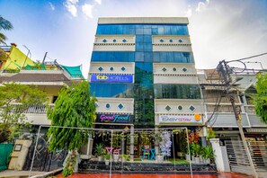 Un hôtel doté d’une façade moderne en verre, un restaurant appelé « Good Food » situé au rez-de-chaussée, et une enseigne « Tab Hotels » au-dessus du restaurant.