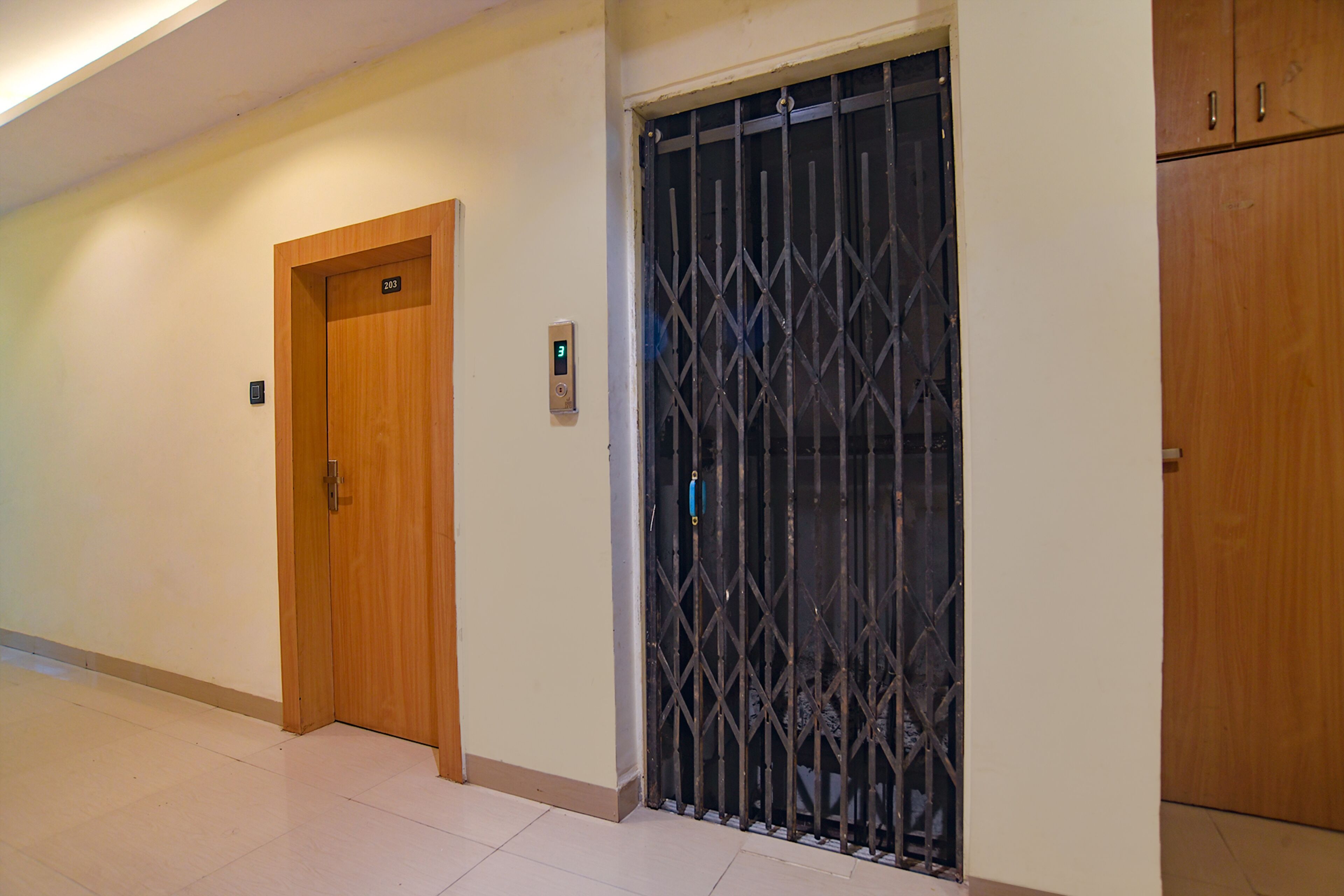 A hallway with a wooden door labeled "203", a metal gate, and a wooden cabinet.