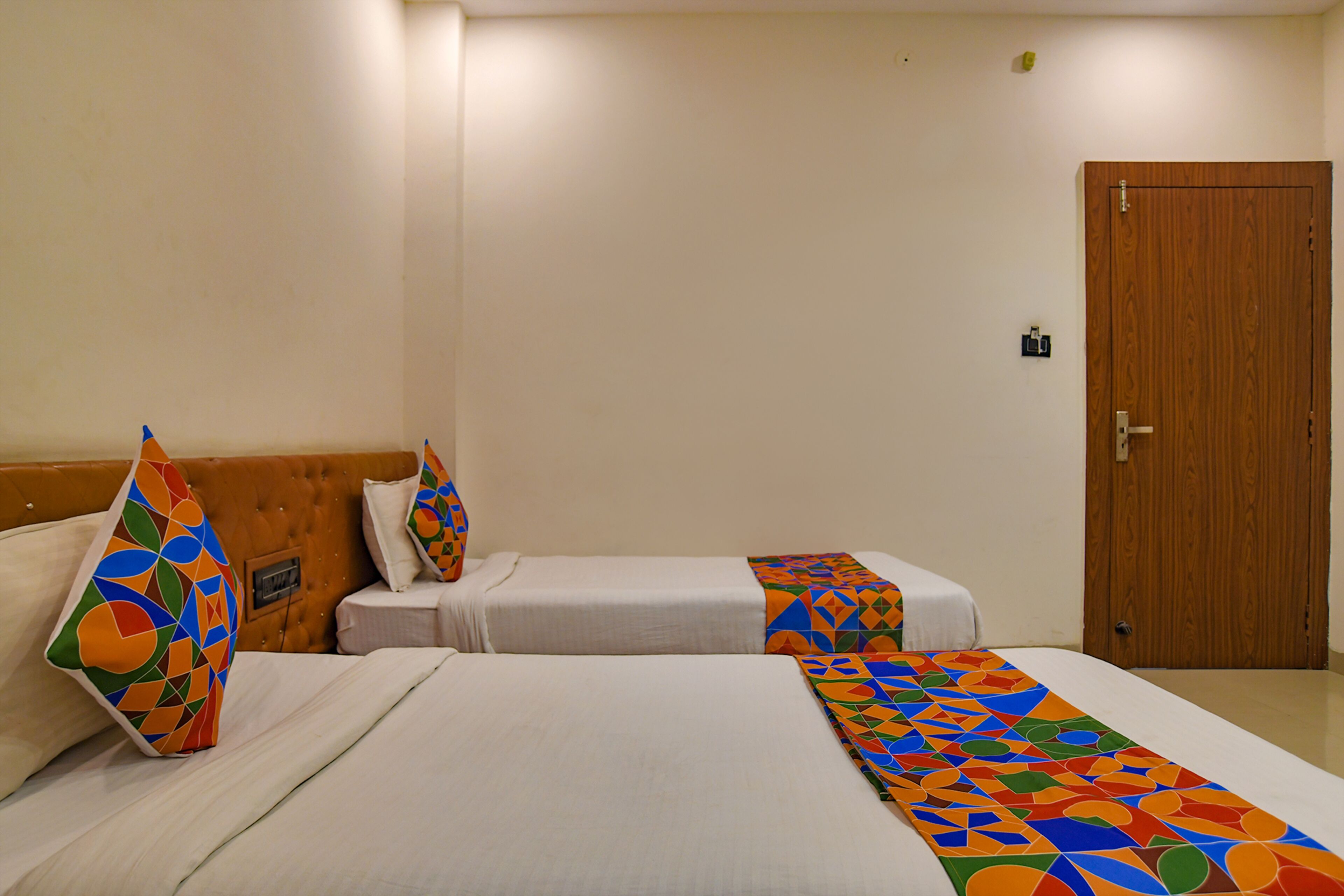 A hotel room with two beds, each with a colorful geometric-patterned throw blanket.