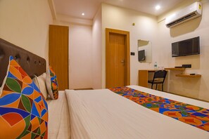 Une chambre d’hôtel équipée d’un lit, d’un bureau, d’une chaise, d’un climatiseur, d’une télévision et d’un miroir.