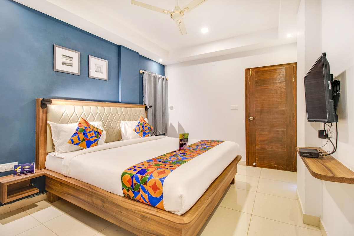 A bedroom with a wooden bed, a ceiling fan, a TV, and a door.