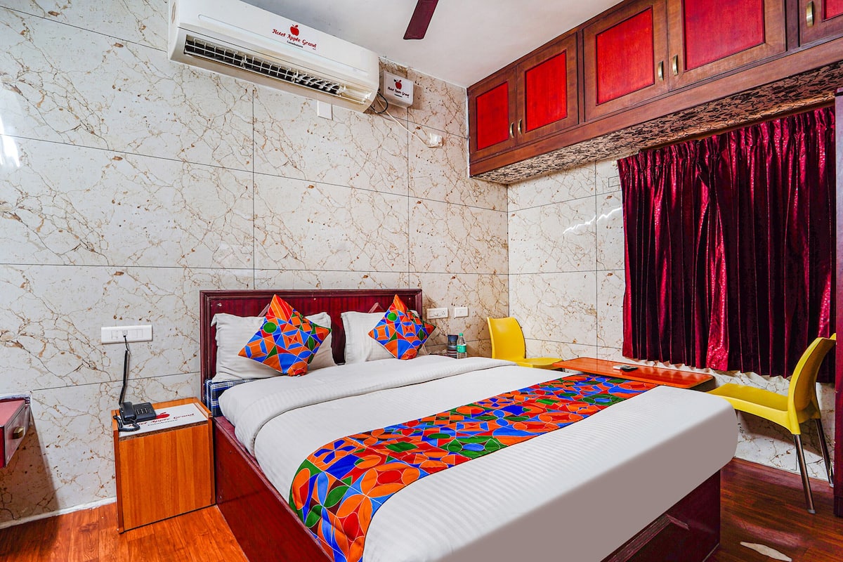 A hotel room with a bed, a nightstand, a chair, a desk, and a window with curtains.