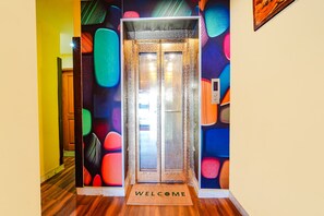 An elevator with a glass door and a welcome mat at the entrance. - Fabexpress Apple Grand (Coimbatore)