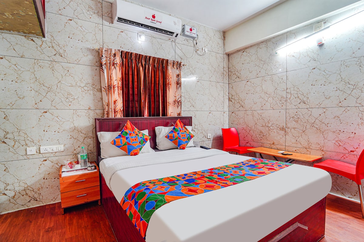 A hotel room with a bed, a desk, a chair, and a window with curtains.