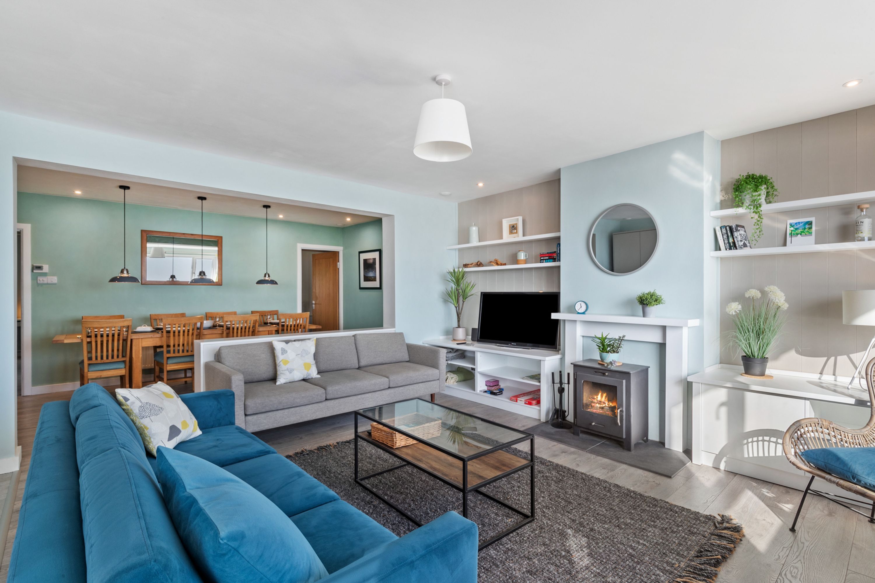 Una sala de estar moderna con sofá, mesa de centro, televisor, chimenea y comedor.