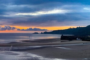 A coastal landscape with a beach, calm sea, and distant hills. - Dolphins Apartment - Spectacular Sea Views (Saundersfoot)