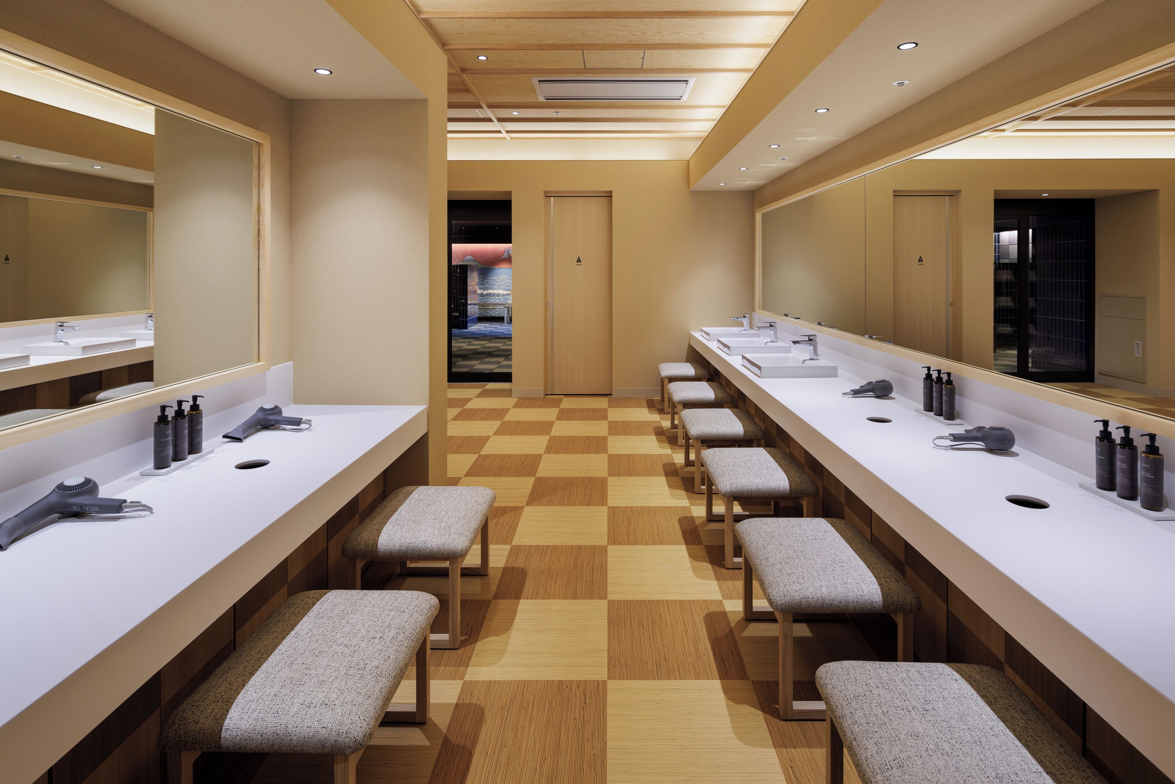 A modern bathroom with multiple sinks, benches, and mirrors.