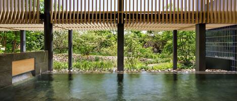 A spa area with a wooden ceiling, stone walls, and a clear pool.