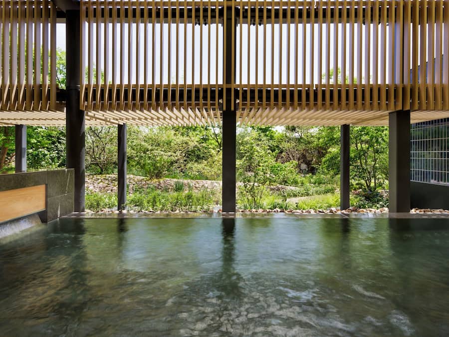 A spa area with a wooden ceiling, stone walls, and a clear pool.