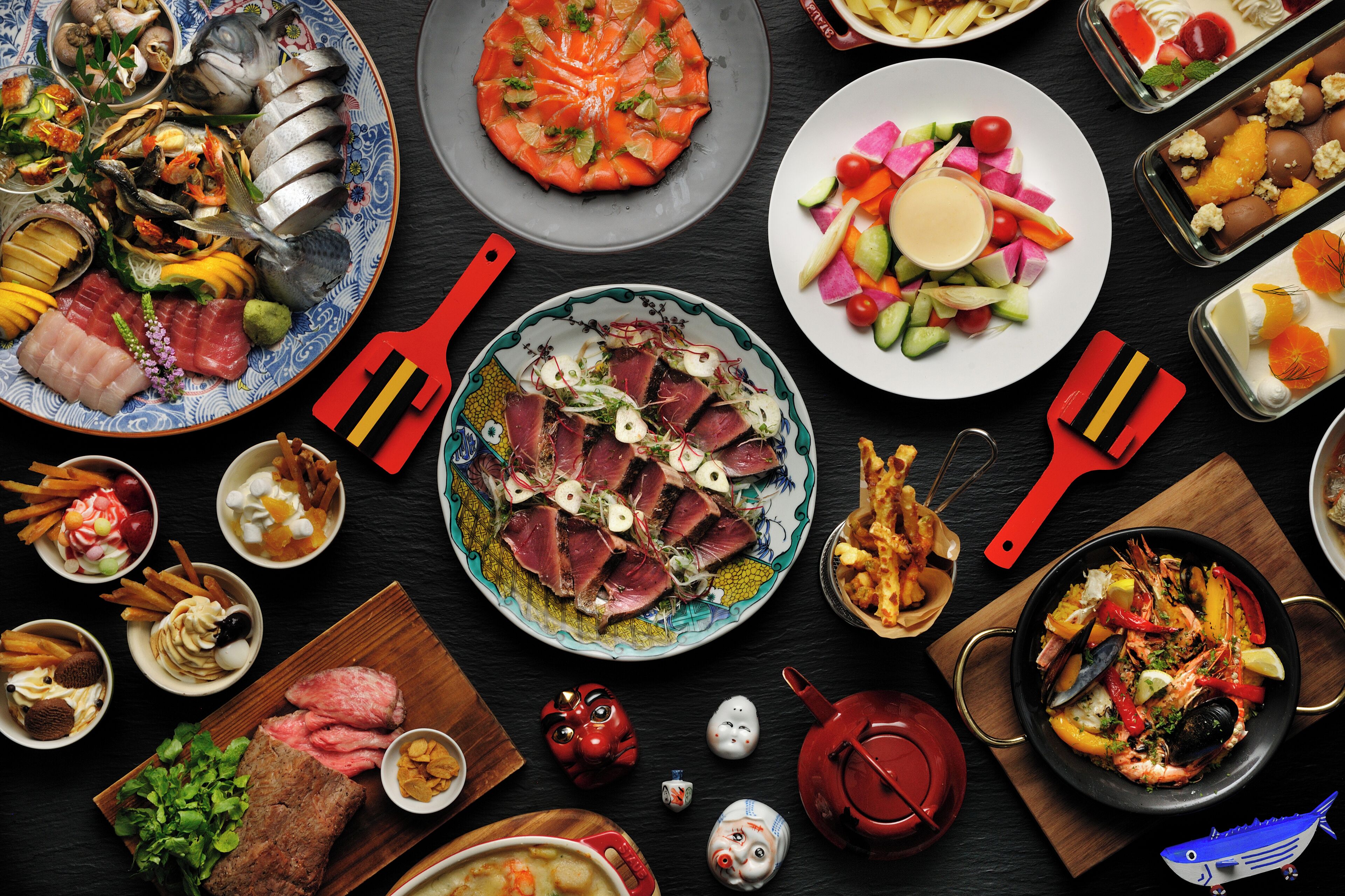 Una variedad de platos que incluyen mariscos, carnes y verduras, dispuestas sobre una mesa oscura.