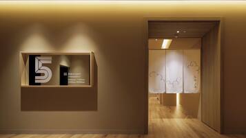 A hallway with a wooden floor, a wall-mounted sign indicating a public bath, and a door leading to another room.